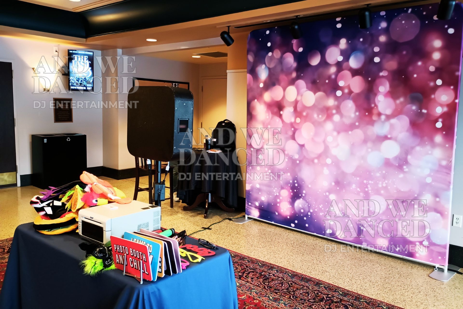 Photo booth setup with a bokeh backdrop, prop table, and booth station.