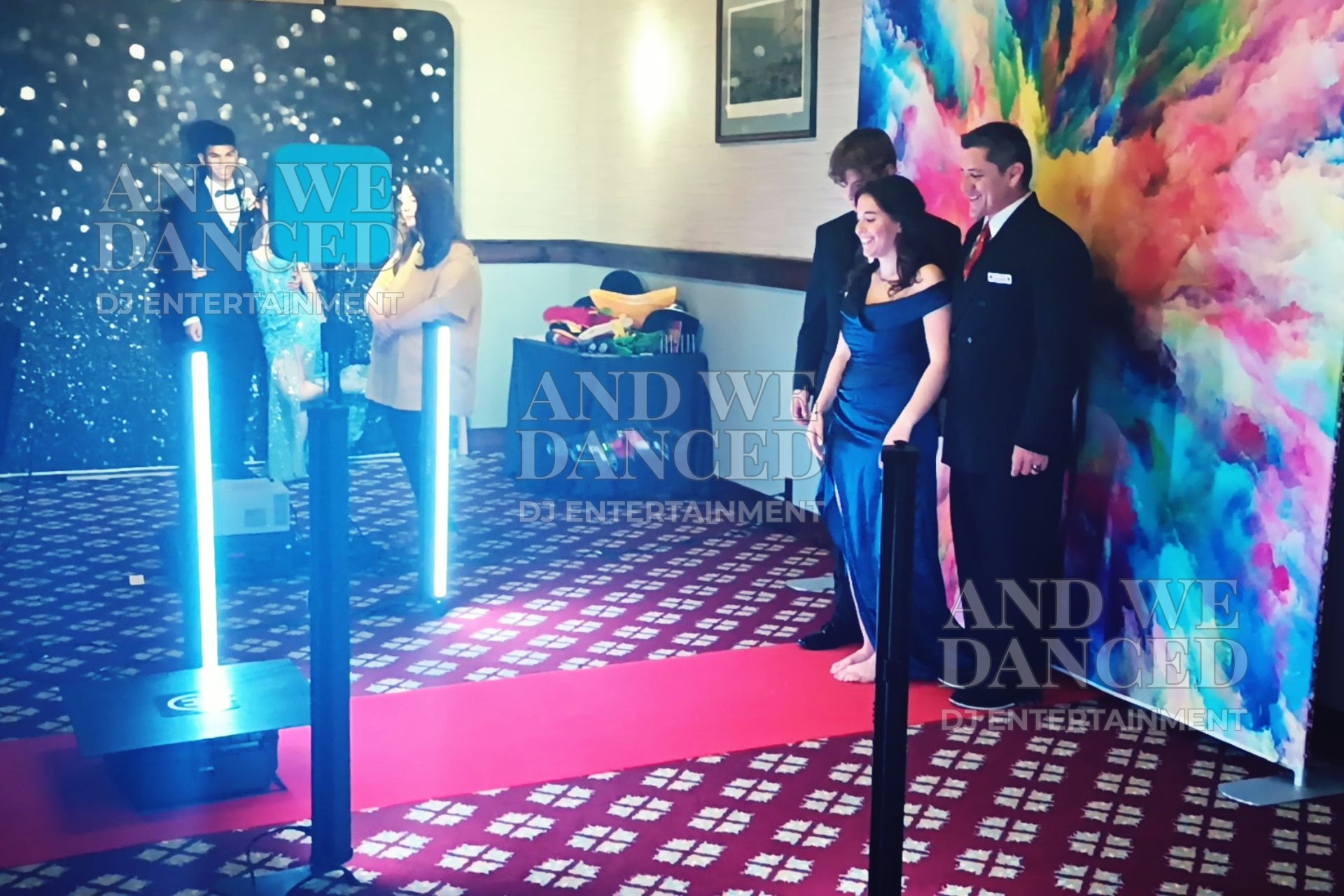 GlamDroneBot doing a reveal while guests pose and the photo booth sits behind.